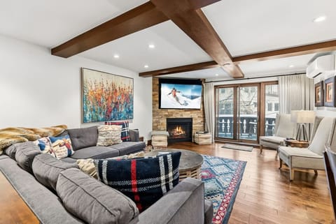 Spacious living room with gas fireplace, large smart TV, and walkout balcony with views of bustling Vail Village!