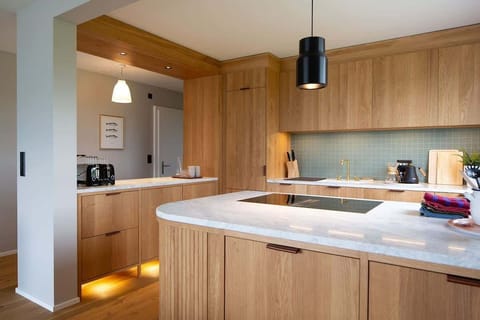 Open kitchen with oak cabinetry, marble tops, Bora hob, oven, fridge and separate freezer.