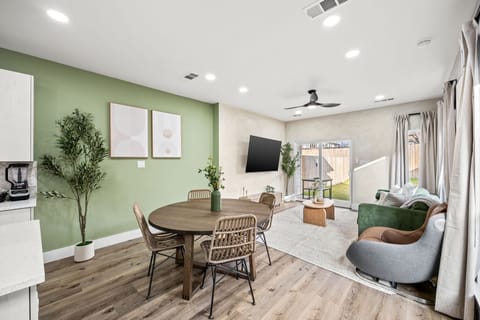 Bright open-plan living featuring a smart TV, full dining set, and direct access to a private outdoor patio.