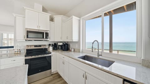 A large window overlooks the ocean, filling the room with natural light and stunning views.