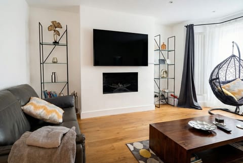 Stylish living room with fireplace, swing chair and bay windows flooding the space with light.