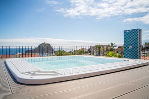Slip into warm bubbles while the coastline glows beyond you.