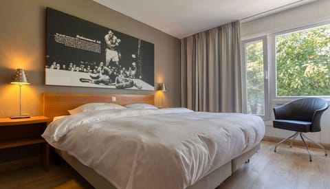 Unwind in a serene king bed with leafy window views.