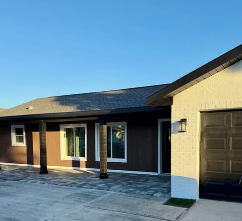 Modern single-story property featuring contemporary brick and metal siding design with covered front porch area and attached garage.
