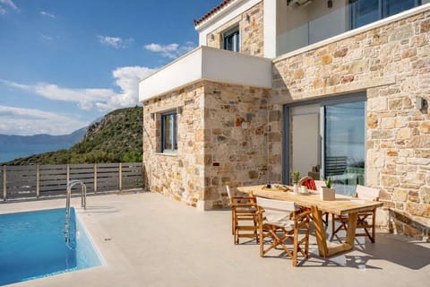 Stone-built villa exterior with private pool and shaded outdoor dining area, set in a peaceful hillside location just 500 m from Balos Beach and with open views across the sea and surrounding landscape.