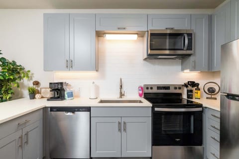 Compact kitchen fully stocked with all essentials and sleek stainless steel appliances—everything you need in a cozy space.