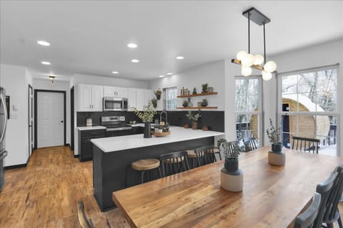 Bright, fully equipped kitchen with a large island + dining table—plus a peek at the outdoor sauna just steps outside.
