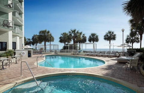 Dive into sunlit pools with ocean breezes steps away.
