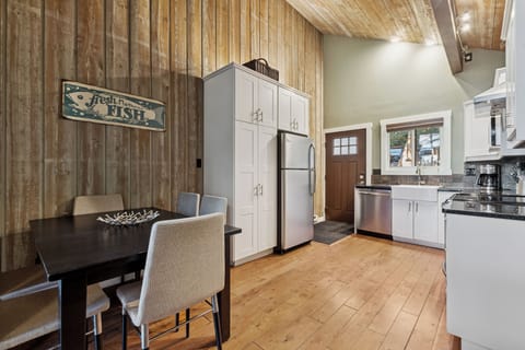 Gather around the handsome dining table in your fully-equipped kitchen, where rustic wood walls meet modern appliances for memorable meals together.