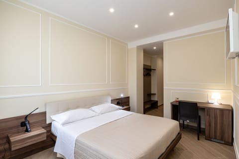 Elegant and comfortable double room located in Verona, furnished in a modern style with a double bed, desk, and refined lighting.