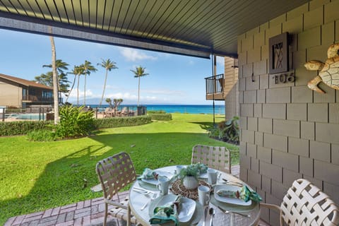 Spacious lanai with dining for four opens to lawn and ocean views.