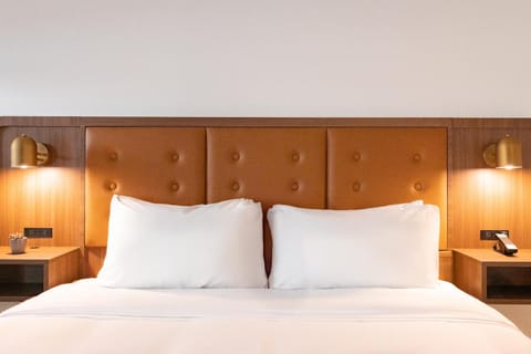 Sink into crisp linens under warm, designer bedside lighting.