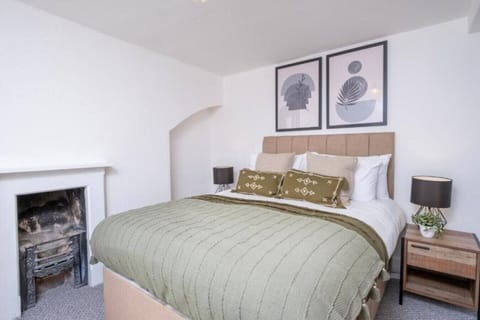 A double bedroom with olive-green bedding and a tan upholstered headboard provides sleeping space for two guests.