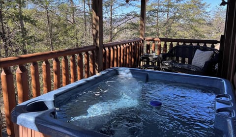Bubbling private hot tub on the deck surrounded by wooded Smoky Mountain scenery at Airport Runway 33 cabin in Pigeon Forge, Tennessee — just 15 minutes from downtown Pigeon Forge.