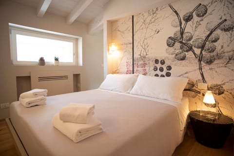 Cozy sleeping area in a studio apartment designed to accommodate up to three people, located in the center of Peschiera del Garda. The room is furnished with a double bed, warm lighting, and modern details, ideal for a comfortable stay near Lake Garda.