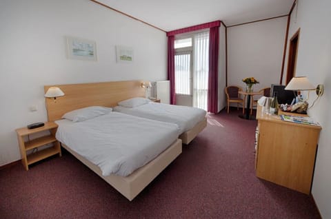 Unwind on crisp twin beds beside soft daylight and seating.