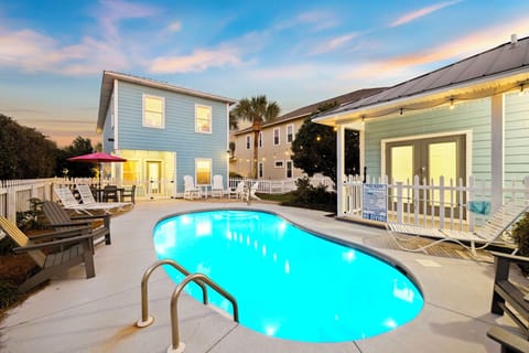 Charming coastal property featuring a private pool surrounded by comfortable lounge chairs and tropical landscaping at twilight.