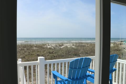 Your private balcony features comfortable blue chairs where you can sip morning coffee while watching waves roll onto the pristine beach just steps away.