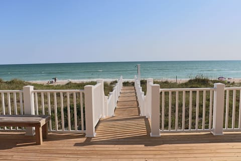 Private boardwalk leads directly to pristine sandy shores where turquoise waters meet endless blue skies.