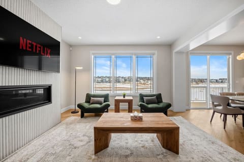 Bright living room with fireplace, large TV, and panoramic neighbourhood views