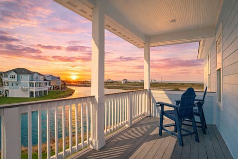 Sunset view from the private balcony at this luxury Galveston beach house rental, featuring outdoor seating and peaceful coastal views in the exclusive beachside community.