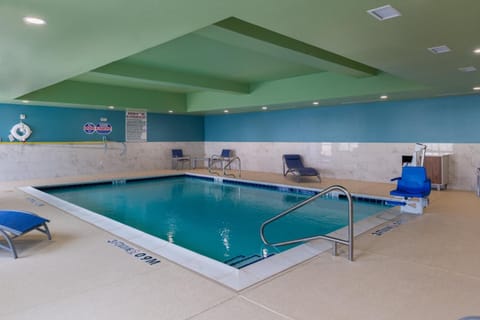 Unwind poolside with comfy loungers under soft indoor lighting.