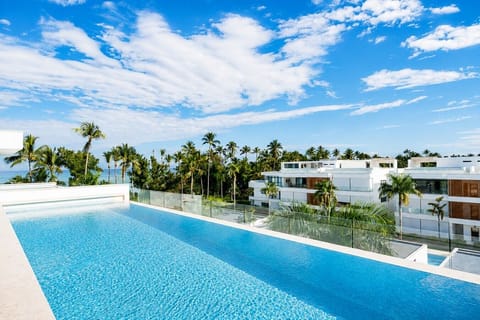Rooftop pool at Sol de Arena F7, offering a refreshing swim with views of the ocean, palm trees, and surrounding residences.