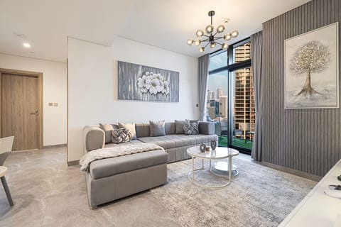 Bright and stylish living room with a plush sectional sofa, chic décor, and floor-to-ceiling windows opening to stunning skyline views—perfect for relaxing after a day in Dubai