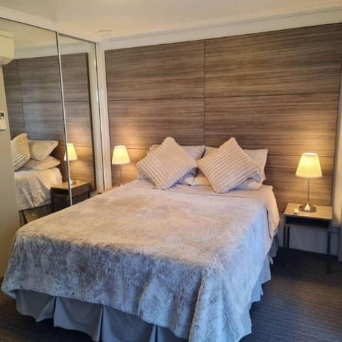 The bedroom is equipped with a queen-size bed, immaculately clean and crisp linens, a smart TV, reverse cycle air conditioning, and double-glazed windows, ensuring an ideal and comfortable environment