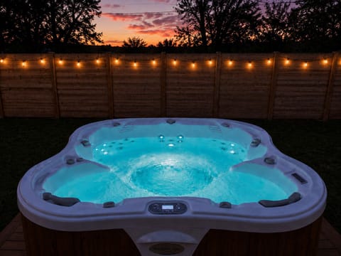 Private hot tub under string lights with a stunning sunset backdrop
