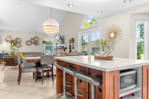 Stylish Kitchen and Living room with a view of the pool, waterfall, fire-pit, outdoor kitchen and gazebo.
