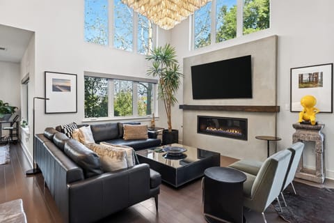 Spacious living room with soaring ceilings, oversized windows, and a sleek fireplace that anchors the space.