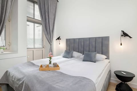 A cozy bedroom with a large bed featuring a gray, quilted headboard, adorned with elegant bedding and a decorative tray of flowers.