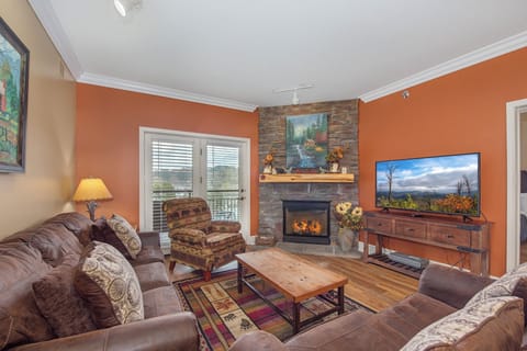 Cozy up in your inviting living room with a crackling stone fireplace, plush seating, and mountain views through French doors.
