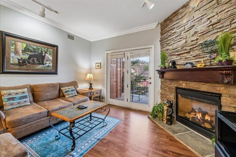 Unwind in your cozy living room with rustic stone fireplace, comfy leather sofa, and private balcony access.