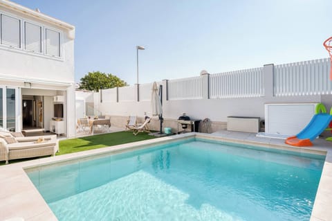 Villa exterior with private heated pool, sun loungers, and barbecue area, perfect for sunbathing and outdoor gatherings