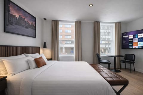 Profitez de cette chambre spacieuse et lumineuse avec son lit douillet, sa grande fenestration et son coin repas. Un mélange parfait de confort moderne et de lumière naturelle.