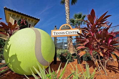 Bright tennis center entrance with giant ball and palms