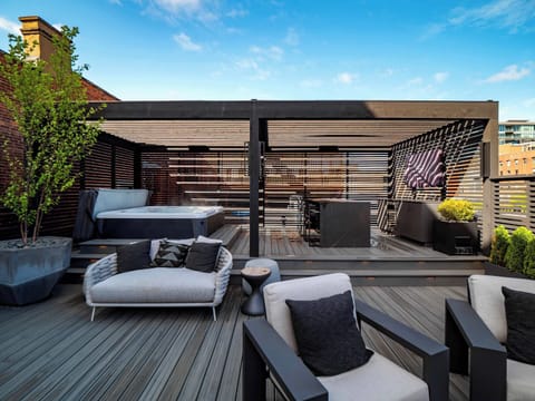 Rooftop lounge w/ cushioned seating & pergola cover, perfect for relaxing in the open air