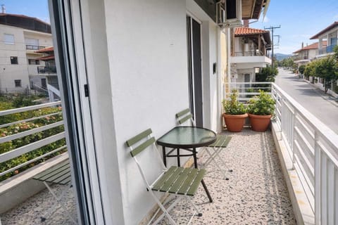 Bright balcony with a small table and chairs overlooking a quiet residential street, offering a relaxing outdoor space to enjoy morning coffee or evening drinks with a view of the greenery