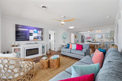 Spacious living room with seating for 6, featuring an oversized sofa, cozy loveseat, and wicker chair, plus a 75” Vizio Smart TV—perfect for relaxing, streaming your favorites, or unwinding after a beach day.