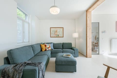 Bright living room with a green sectional sofa and natural wood accents.