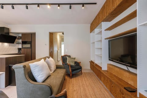 Cozy living area with a vintage armchair and built-in wooden shelving around the television