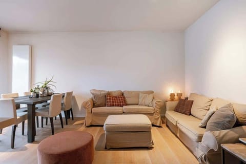Cozy living room with beige sofas and a dining area featuring a dark wood table.