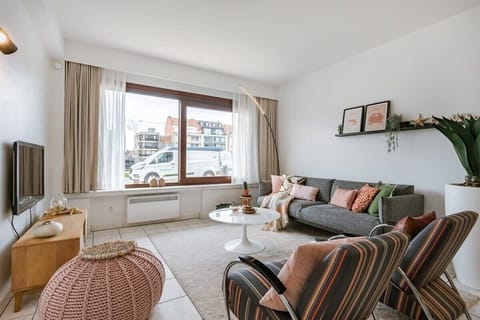 Modern living room with a large window and cozy seating area.