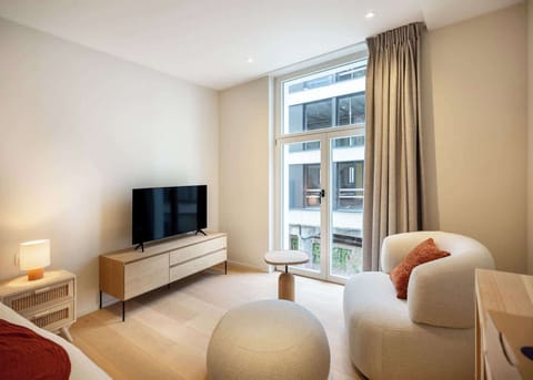 Modern living area with natural light from large windows and cozy seating.