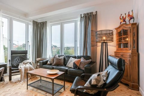 Cozy living room with leather seating and large windows offering natural light.