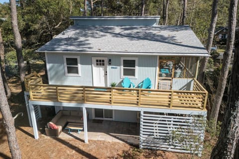 Charming coastal-style home with large deck, outdoor seating, and serene forest views