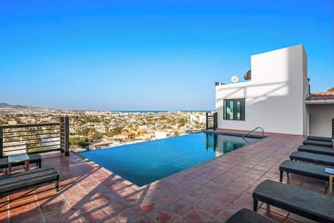 Shared Infinity pool w/ sun loungers & sweeping city views under clear blue skies