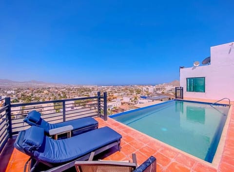 Shared poolside terrace w/ loungers & sweeping views, perfect for relaxing under clear skies